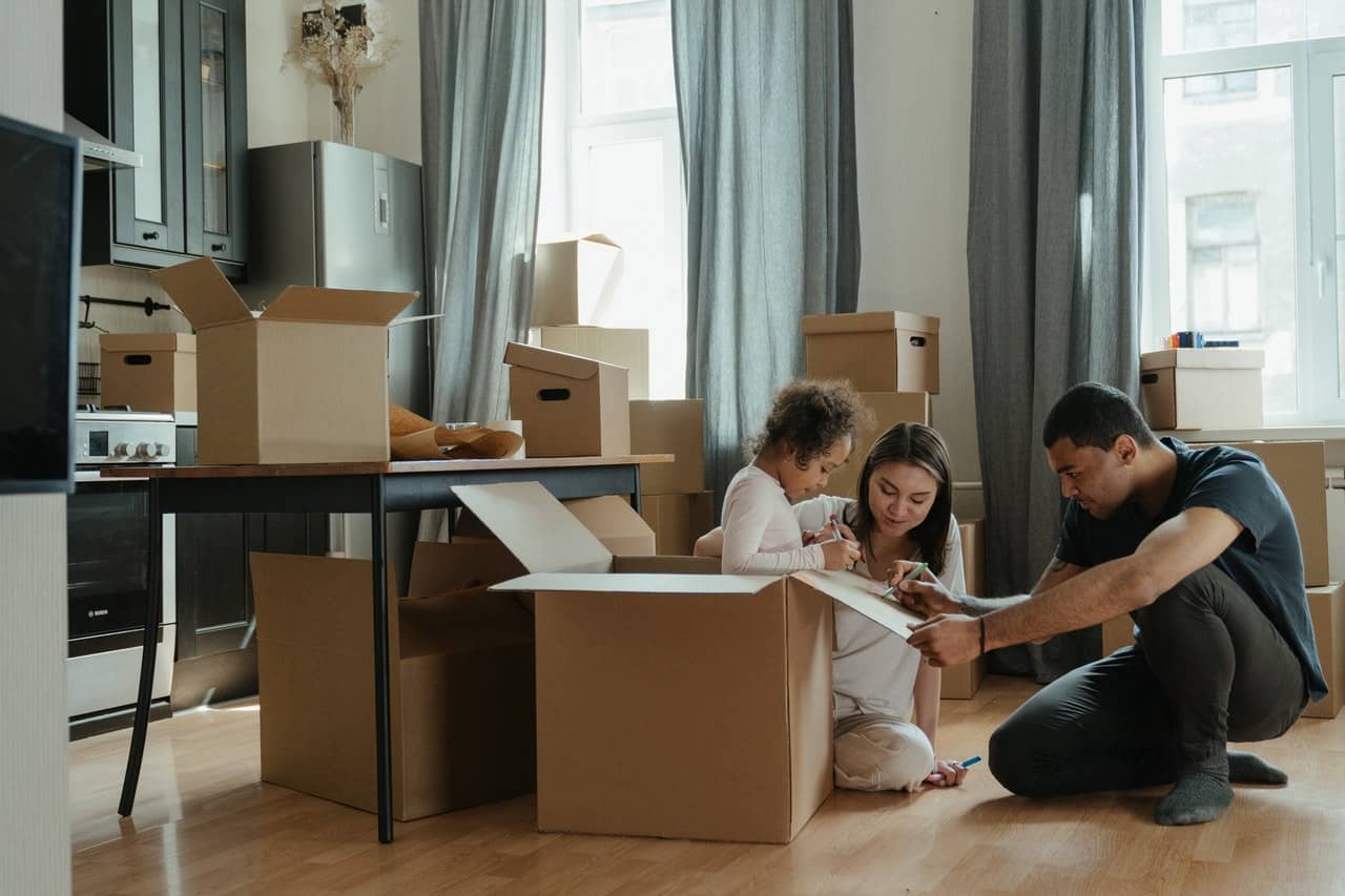 family sitting around a bunch of moving boxes preparing to move out of their current home.