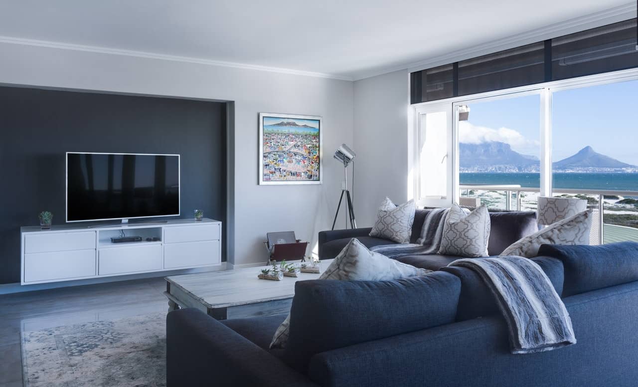Image of a clean and tidy living room illustrating the standard cleaning package. There is a blue couch, nicely folded towel, and cleaned up carpet.